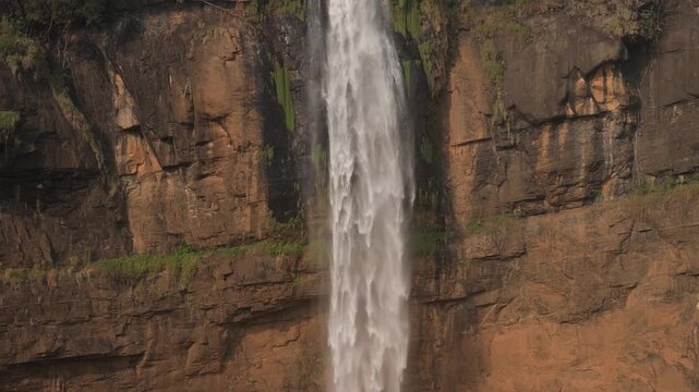 Aerial view of Cikanteh Waterfall cascading down steep rocky cliffs with lush green vegetation in Sukabumi, West Java, Indonesia.