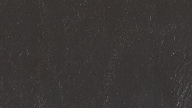 4k horizontal slow motion footage of a dark gray leather texture with lots of grain, wrinkles, and worn edges