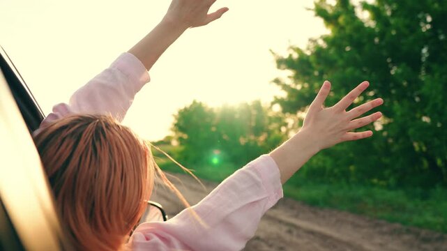 Happy woman student drives towards adventure. Young woman passenger catches wind with hands from car window. Family trip, teenage girl traveling car. Family vacation. People on vacation travel, road