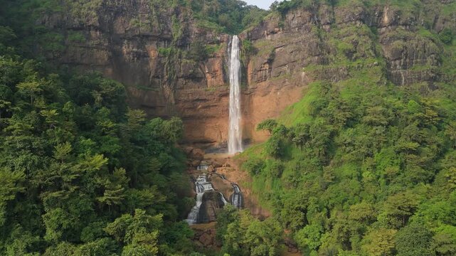 Aerial view of Cikanteh Waterfall cascading down a rocky cliff surrounded by lush tropical forest in Sukabumi, West Java, Indonesia.