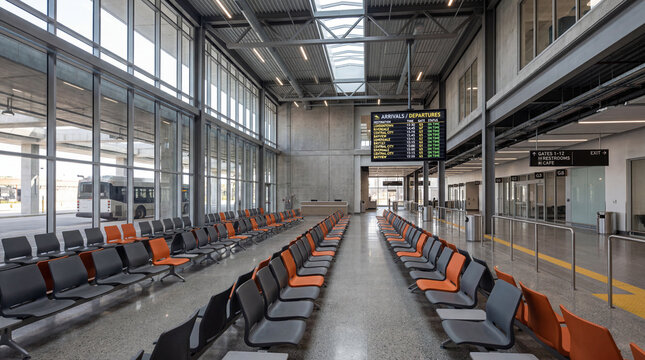 Modern bus terminal lounge with molded plastic seating rows and large digital arrival board display