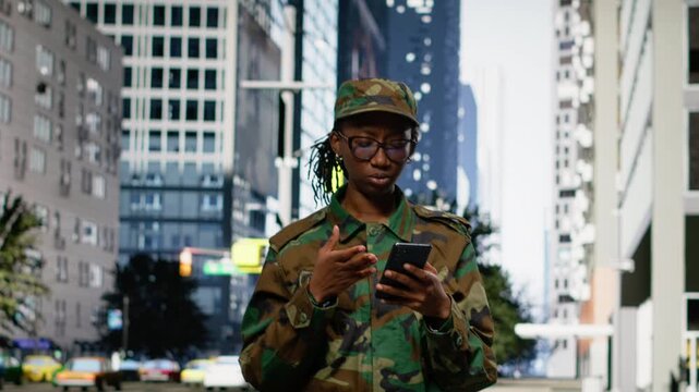 Black military soldier devastated after reading bad news on her phone, sad and depressed woman worried about future mission and global conflict. Army officer crying on city street downtown.