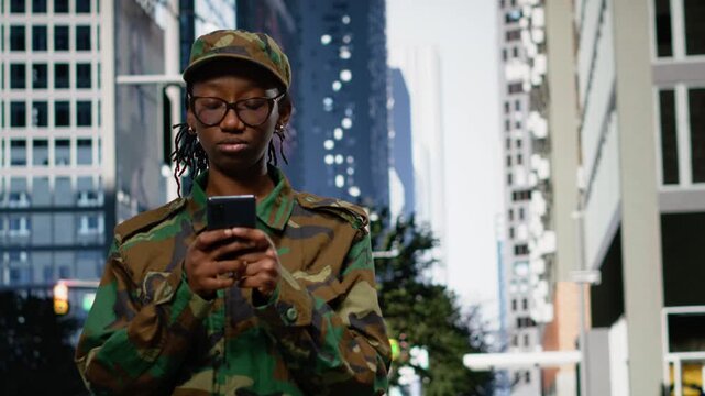 Delighted army soldier outdoors gasping after receiving good news on phone, returning home and feeling happy. Thrilled woman on city street surprised by message on smartphone.