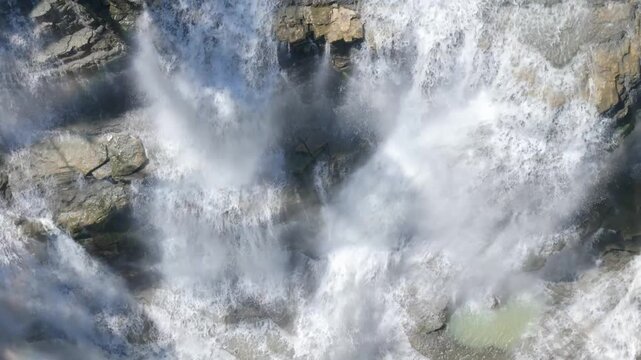 Aerial view of Cigangsa Waterfall with rushing white water and mist over dark rocks in Sukabumi, West Java, Indonesia.