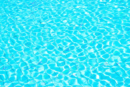 Bright blue swimming pool water surface with rippled wave reflection over mosaic tiles grid pattern for summer background