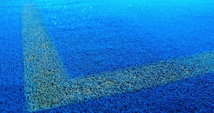Extreme super slow motion close-up of a tennis or padel ball bouncing near the court line. Detailed blue surface texture captured at 1000fps with dynamic sports action in macro detail.