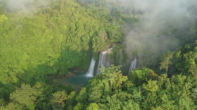 Aerial view of Cikaso Waterfall nestled in a lush tropical forest with mist rising from the dense green canopy under soft morning light Sukabumi, West Java, Indonesia.