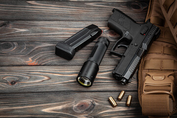 Obraz premium Tactical handgun with a magazine, flashlight, and ammo on a dark wooden back