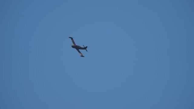 Camouflage propeller airplane banking hard against a clear bright blue sky background
