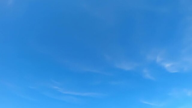 An expansive azure blue sky with wispy white clouds, slowly drifting above pristine pure white copy space, bathed in bright optimistic daylight. Concept of limitless potential and clear vision