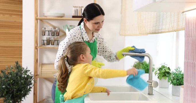 Spring cleaning. Smiling mother and daughter wiping surfaces with rags in kitchen