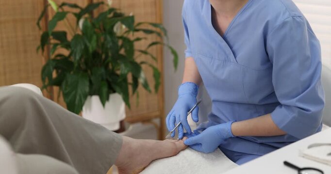 Woman undergoing toenail treatment during visit to podiatrist in clinic, closeup. Camera moving down