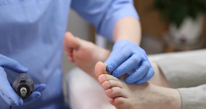 Woman undergoing foot treatment during visit to podiatrist in clinic, closeup. Camera moving in