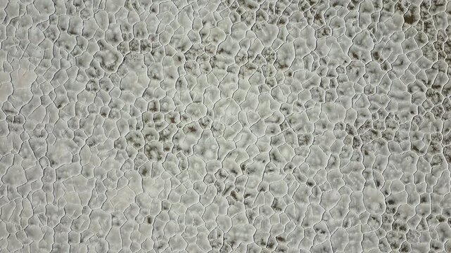 Aerial view of Salinas Grandes salt flats showing hexagonal crust patterns and white mineral textures in Tumbaya, Jujuy, Argentina.