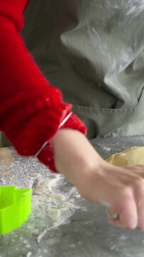 Vertical video: Reaching for rolling pin, cook in apron rolling dough to flatten on floured counter