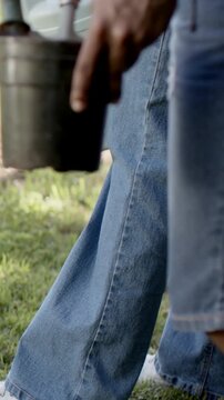 Vertical video: Starting to walk, two people carrying metal pail and pale blue bucket across yard