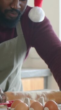 Vertical video: Using blue jar man in maroon knit rolling dough in kitchen with pin for cookies