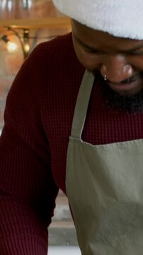 Vertical video: Dusting flour, baker at home in Santa-hat rolling dough with pin, holiday baking