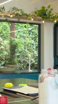Vertical video: Adult whisking girl in apron scooping sugar from jar, baking at home, copy space