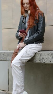 Vertical video: Checking woman in leather tapping pink phone reading texts after camera pan, bag