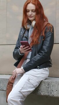Vertical video: Sitting redhead using phone on bench in leather, woman entering and eating salad