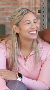Vertical video: Offscreen friend speaking, woman in pink top laughing, smiling in studio with watch