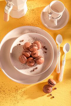 Sweet and delicious coffee macarons on plate on yellow background.