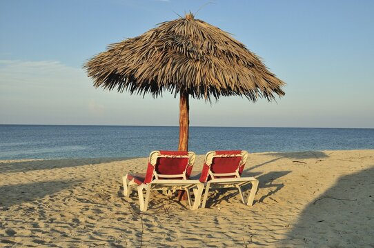 Empty sunbeds under a parasol on the beach of Playa Anc&oacute;n near Trinidad, Cuba, Caribbean