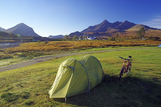 A tent and a bicycle stand on a green meadow with mountains in the background, ideal for camping, October, Slichigan, Cullins, Hebrides, Isle of Skye, Hebrides, Scotland, United Kingdom
