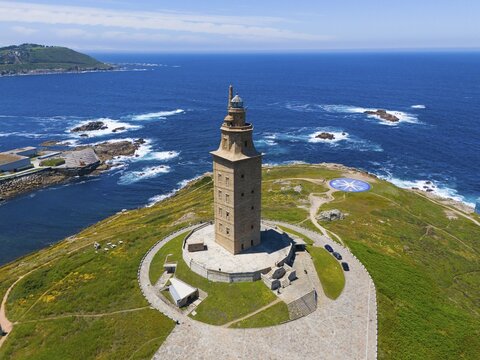 Ancient lighthouse on a land mass surrounded by crystal blue ocean and green vegetation under a clear sky, aerial view, Torre de H&eacute;rcules, Torre de Hercules, Roman Tower of Hercules, A Coru&ntilde;a, A Coruna, La Coru&ntilde;a, La Coruna, Galicia, Spain