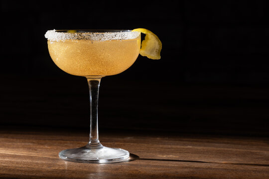 Lemon drop cocktail in chilled martini glass garnished with a lemon twist, and golden edible glitter with a partial sugar rim
