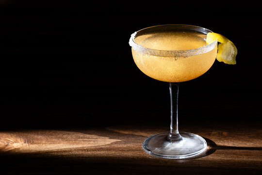 Lemon drop cocktail in chilled martini glass garnished with a lemon twist, and golden edible glitter with a partial sugar rim