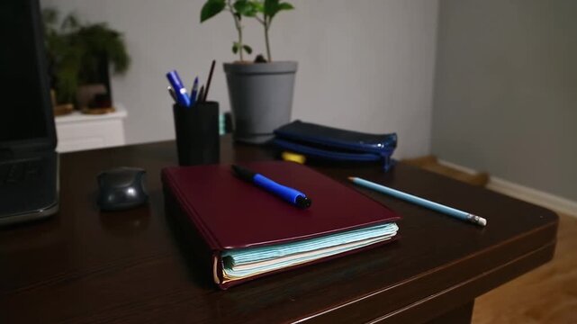 Office work desk with a wood table. Computer, notebook with blue pen, pencil and flower in pot in the study home room. Education, learning concept in different angles. Closeup