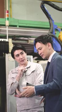 製造業の工場現場で作業着の技術者と営業が機械を見ながら見積もりや修理、メンテナンスの金額を悩む考えるのシーンの縦動画