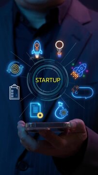 Businessman holding smartphone to show neon line banner of startup concept with icons of startup, innovation, funding, business plan, prototype, investment, launch and pitch.