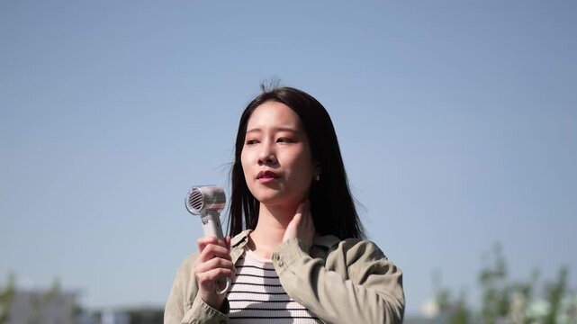 暑い夏の日にハンディファンで涼む女性