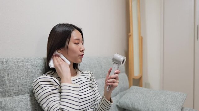 汗をハンディファンとハンカチで乾かす女性