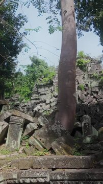 Ancient stone ruins of Prasat Beng Mealea overgrown with vegetation in Cambodia. The crumbling structures hint at a lost civilization and the passage of time.