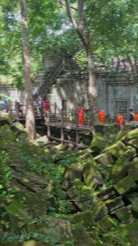 Two tourists explore the ancient ruins of Beng Mealea temple in Cambodia. The temple is known for its unrestored state, allowing visitors to experience its jungle-clad beauty.