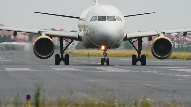 Detailed front view of a commercial passenger airplane on the tarmac showing the nose landing gear and large jet engines