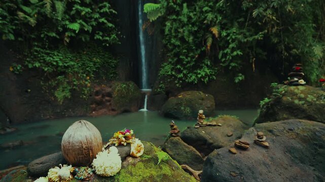 Scenic tropical waterfall cascading in deep jungle canyon with traditional flower offering 4K