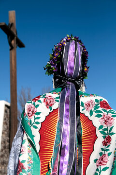 Matachine dancer seen from behind in floral shawl and ribbons