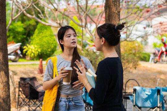 Two Asian students talking together during going classroom