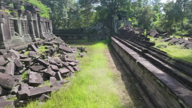 Ancient stone ruins of a temple complex in Beng Mealea, Cambodia, overgrown with jungle vegetation, showcasing the effects of time and nature.