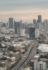 Fototapeta premium A sprawling concrete artery cuts gracefully through the urban landscape, carrying the early morning rhythm of the city forward. Above the low-rise neighborhoods, a formidable wall of glass and steel t