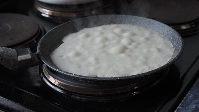 Close-up of batter of pancake batter bubbling in hot pan while baking pancakes