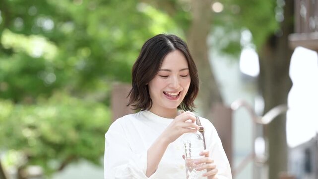 新緑の屋外で水分補給をする女性の健康的なライフスタイルイメージの動画