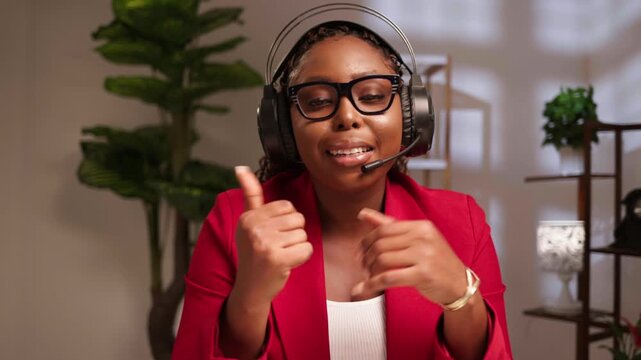 African woman wearing headset and glasses, smiling while talking during an online meeting