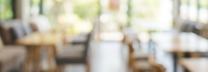 Fototapeta premium A blurred interior view of a modern restaurant or cafe, featuring wooden tables and comfortable seating. Natural light illuminates the space, creating a warm ambiance.