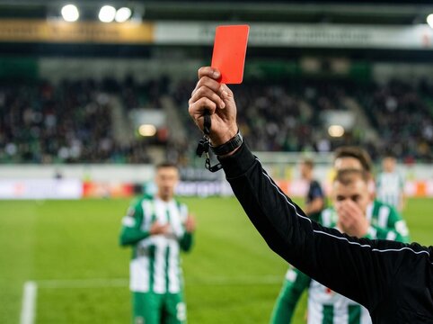 Soccer referee showing a red card during an intense football match, symbolizing discipline, authority, and fair play on the field